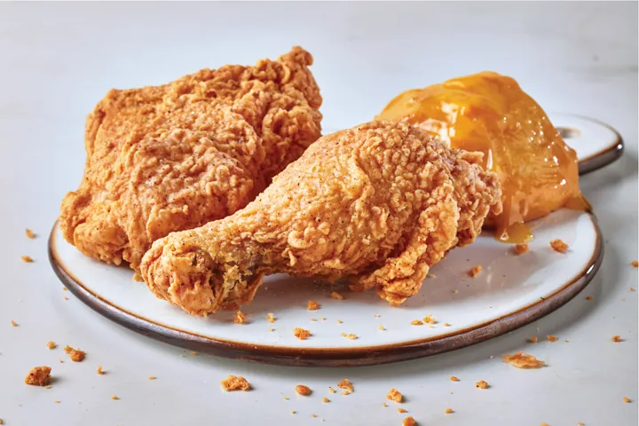 Two pieces of bone-in fried chicken with a honey biscuit